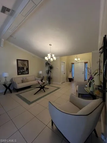 Living area with lofted ceiling, light tile patterned floors, hanging lights, and crown molding