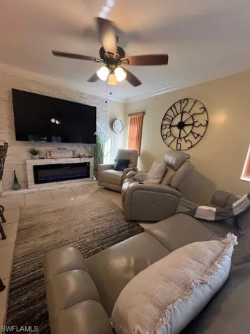 Living area with a ceiling fan, crown molding, and tile patterned floors