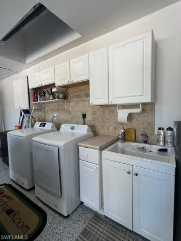 Laundry area with washer and clothes dryer, cabinet space, and dark speckled floor