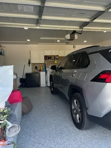 Garage featuring a garage door opener and fridge