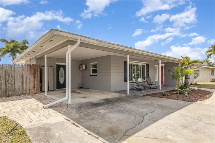 Ranch-style home featuring a carport, a porch, and an AC wall unit