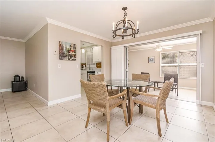Tiled dining space with ceiling fan with notable chandelier, ornamental molding, and sink