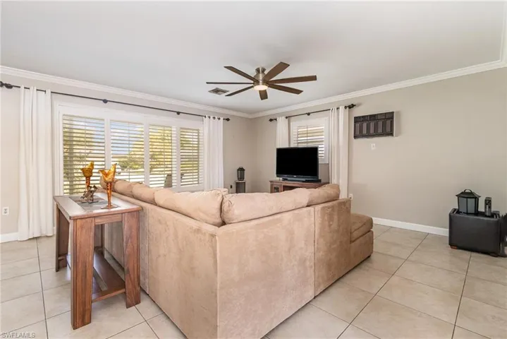 Tiled living room with ornamental molding and ceiling fan