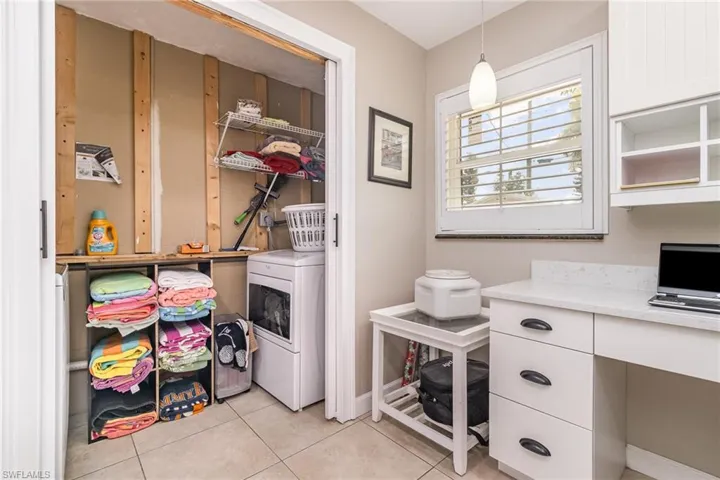 Clothes washing area featuring washer / dryer and light tile patterned flooring