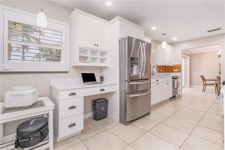 Kitchen with white cabinetry, stainless steel refrigerator with ice dispenser, and pendant lighting