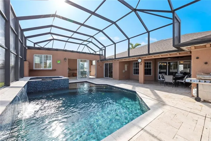 View of pool featuring a patio, outdoor dining area, a pool with connected hot tub, and a lanai