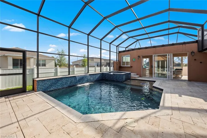View of swimming pool featuring a pool with connected hot tub, fence, a patio, and lanai enclosure