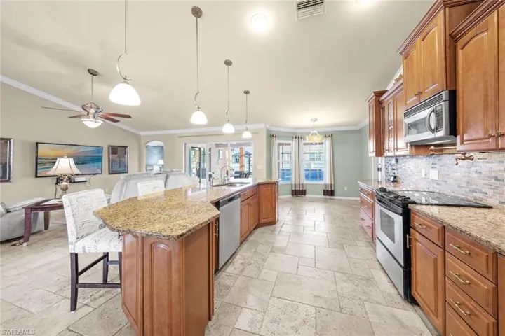 Kitchen with stone tile floors, ornamental molding, a sink, and stainless steel appliances