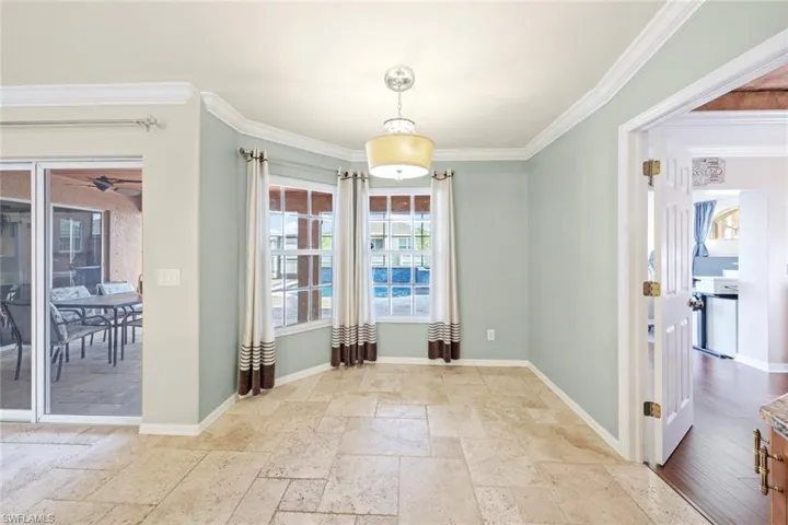 Unfurnished dining area featuring crown molding, stone tile floors, baseboards, and a ceiling fan