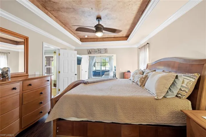 Bedroom with a tray ceiling, ceiling fan, and ornamental molding