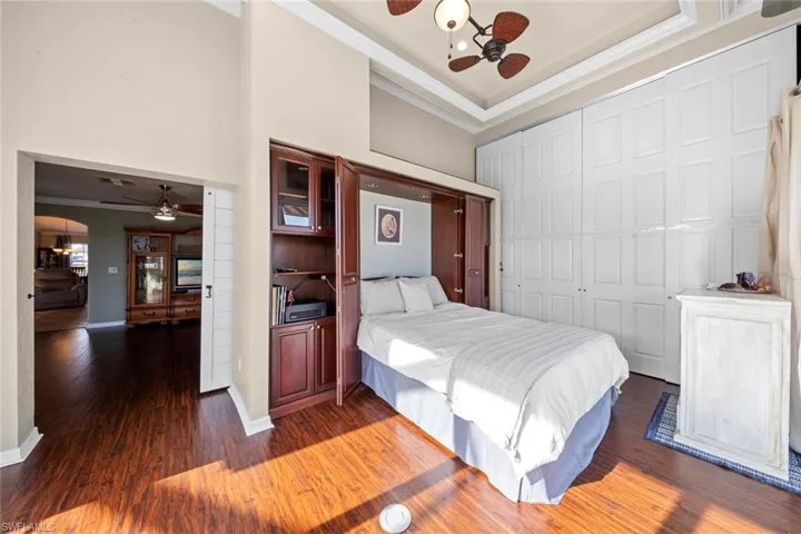 Den, Bedroom, or craft area with baseboards, a closet, a high ceiling, crown molding, and wood finished floors