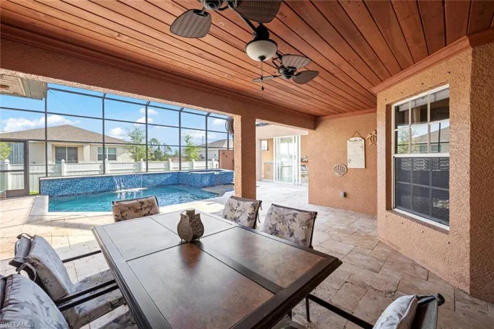 View of patio featuring a pool with connected hot tub, outdoor dining area, a lanai, and a ceiling fan
