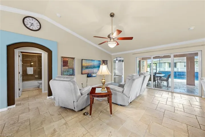 Living area featuring a ceiling fan, baseboards, lofted ceiling, and stone tile flooring