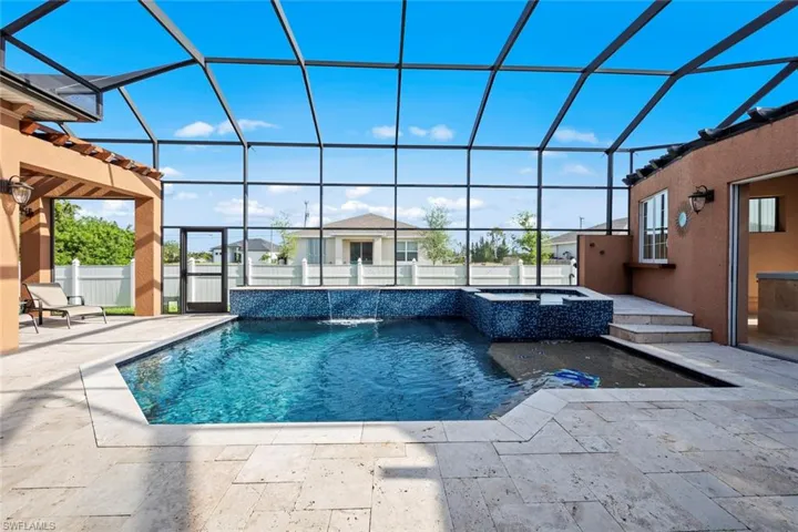View of swimming pool featuring a patio area, fence, a pool with connected hot tub, and a lanai