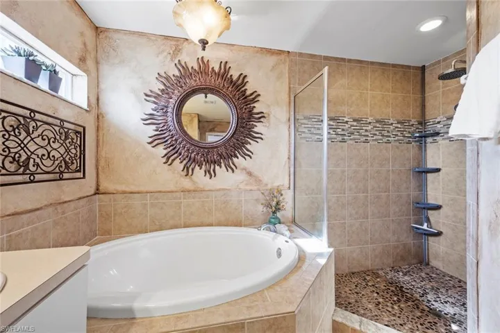 Full bath featuring vanity, a bath, and a tile shower