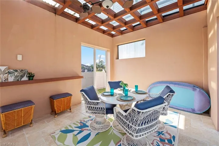 Dining area featuring ceiling fan, beamed ceiling, stone tile flooring, and coffered ceiling