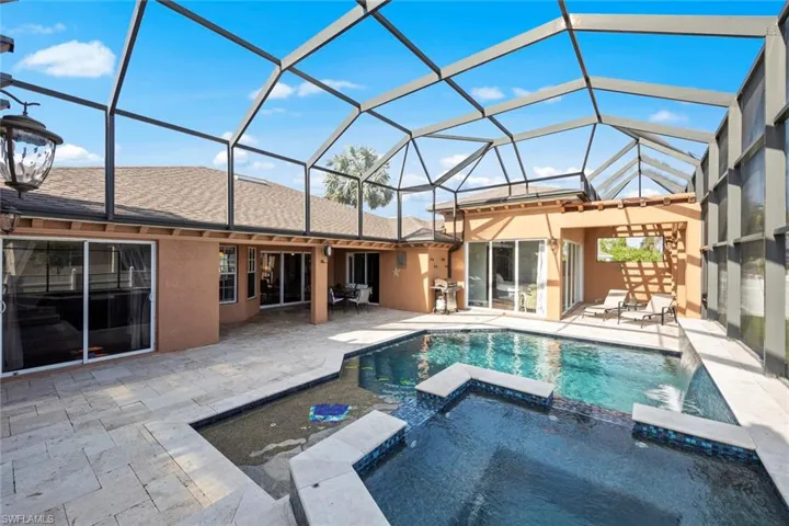 Back of property with a patio, a pool with connected hot tub, and stucco siding