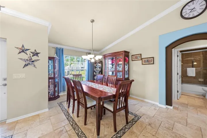 Dining space featuring ornamental molding, stone tile flooring, baseboards, and a notable chandelier