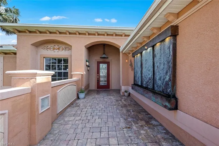 View of exterior entry featuring stucco siding and water feature