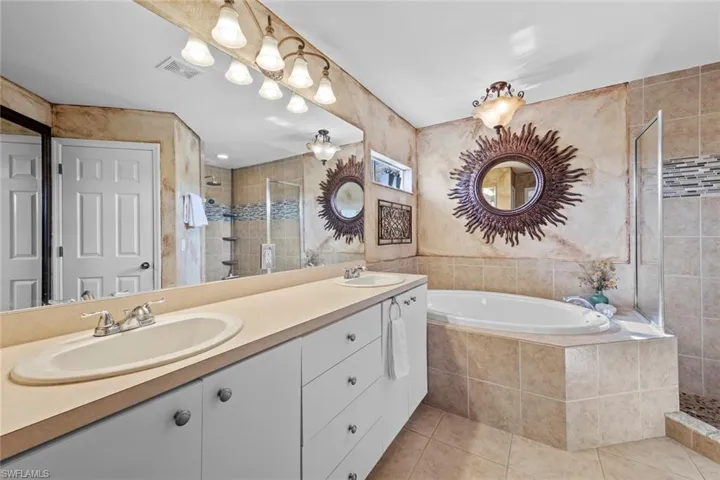 Bathroom with tile patterned floors, visible vents, a sink, and a stall shower