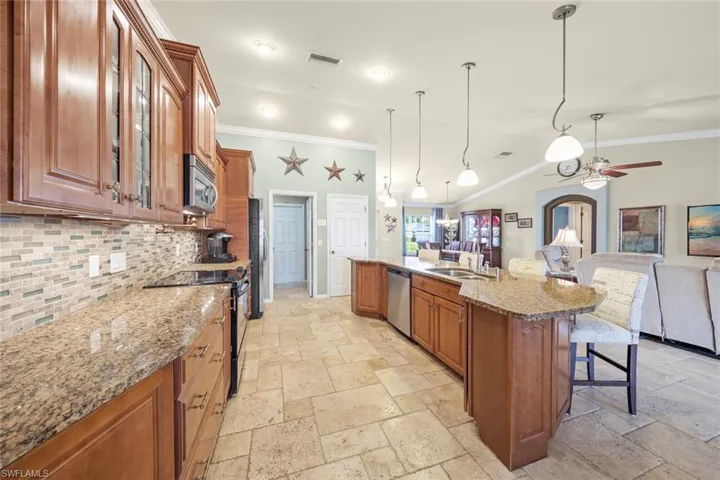 Kitchen with appliances with stainless steel finishes, a kitchen bar, brown cabinets, stone tile floors, and decorative backsplash