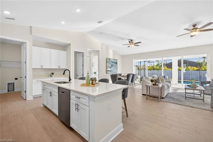 Kitchen featuring white cabinets, an island with sink, wood tiled floors, a kitchen bar, and lofted ceiling