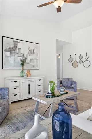 Living area with ceiling fan, wood finished floors, and lofted ceiling