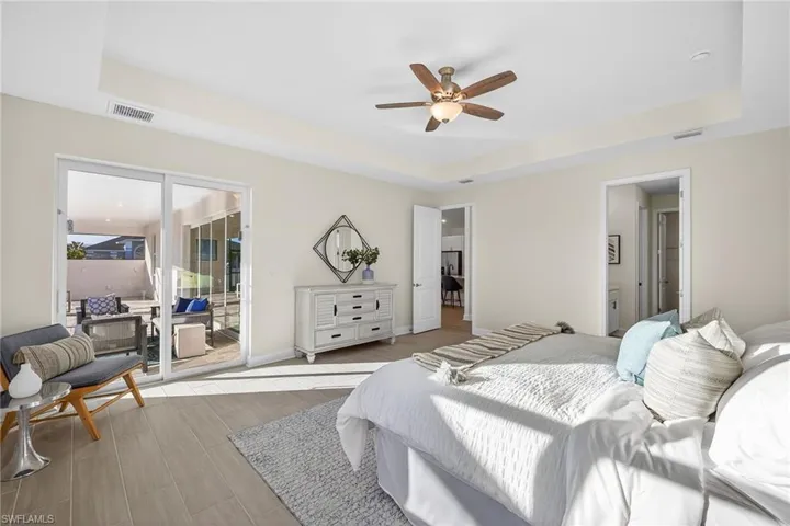 Bedroom with a raised ceiling, ensuite bath, ceiling fan, and access to exterior