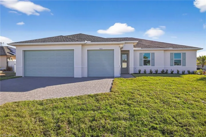 View of front of home with decorative driveway, a garage, a front lawn, and stucco siding