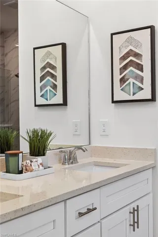 Full bathroom featuring double vanity and a marble finish shower