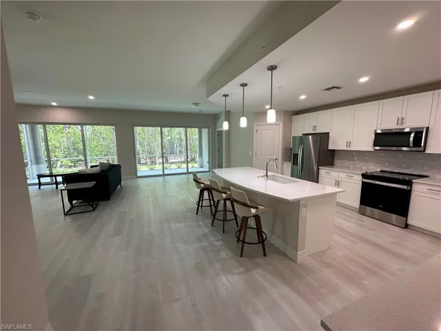 Kitchen with stainless steel appliances, white cabinets, tasteful backsplash, and open floor plan