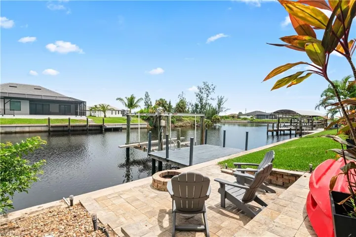 Dock area featuring boat lift, a water view, a fire pit, and a residential view