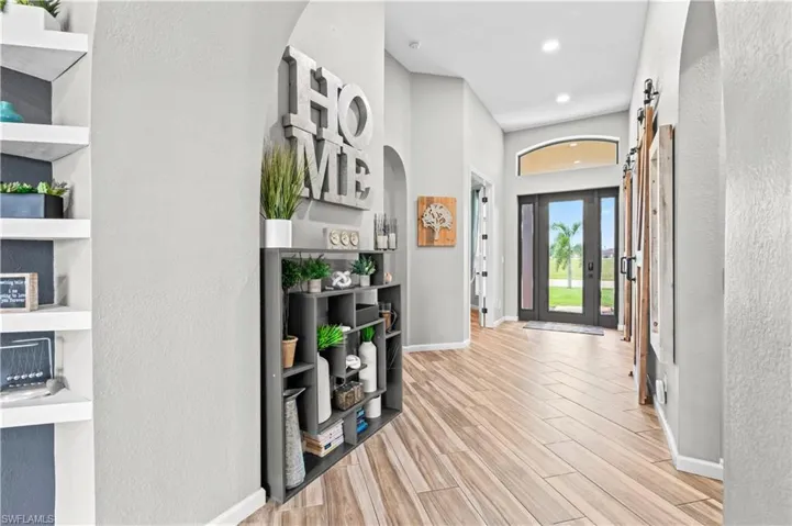 Entryway with a barn door, a textured wall, wood finish floors, and arched walkways