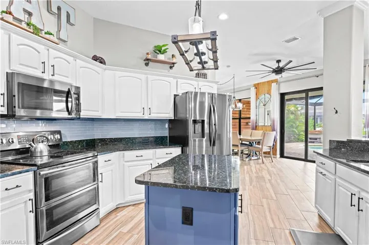 Kitchen with appliances with stainless steel finishes, pendant lighting, white cabinetry, dark stone counters, and recessed lighting