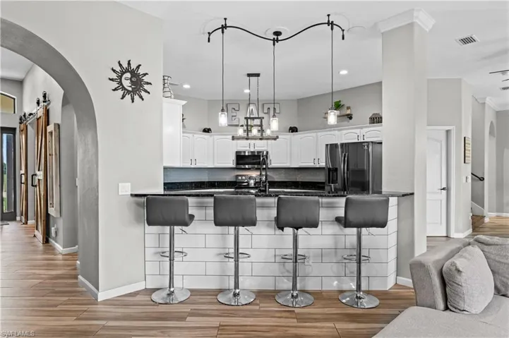 Kitchen featuring arched walkways, a barn door, backsplash, hanging light fixtures, and stainless steel appliances