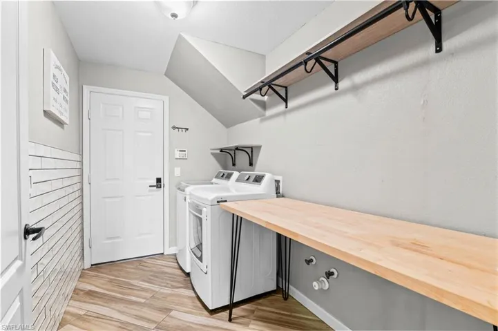 Laundry area with light wood-style flooring and washing machine and clothes dryer