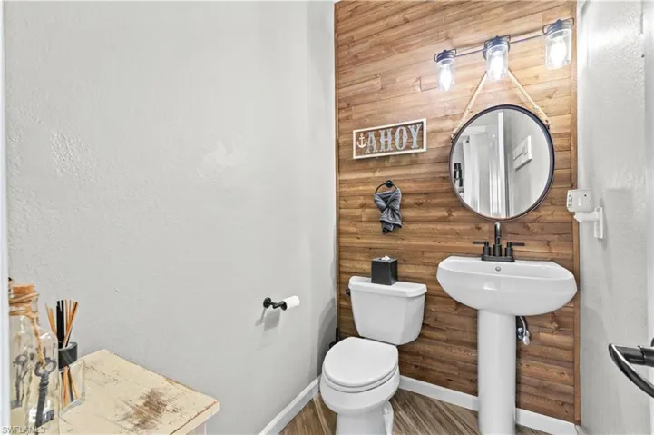 Half bathroom featuring wooden walls and a textured wall