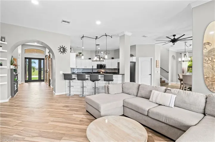 Living room with arched walkways, a chandelier, light wood-style flooring, recessed lighting, and stairway
