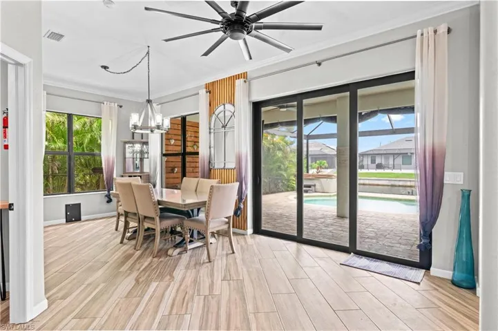 Dining room featuring crown molding, wood finish floors, ceiling fan, a chandelier, and a sunroom
