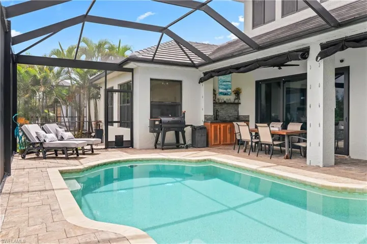 Swimming pool with a lanai, a sunroom, a grill, and a patio