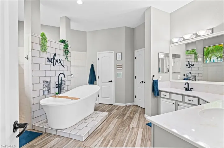 Bathroom with a freestanding bath, vanity, light wood finished floors, and walk in shower