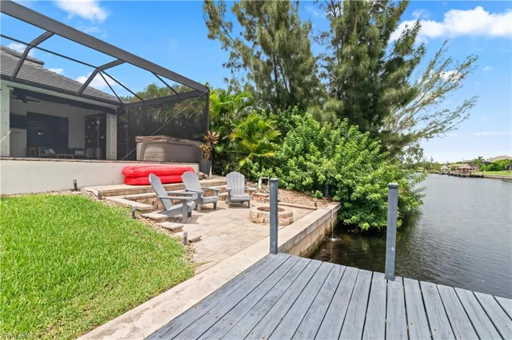 Dock area with a lanai, a patio, a water view, a sunroom, and a lawn