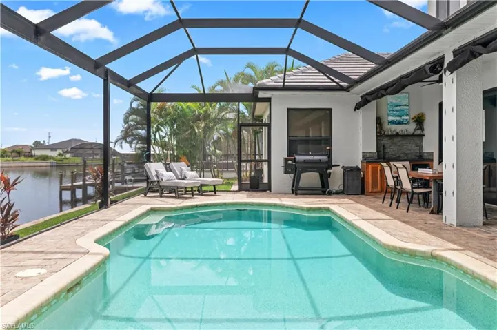 Outdoor pool featuring a lanai, a sunroom, grilling area, a patio area, and outdoor dining space