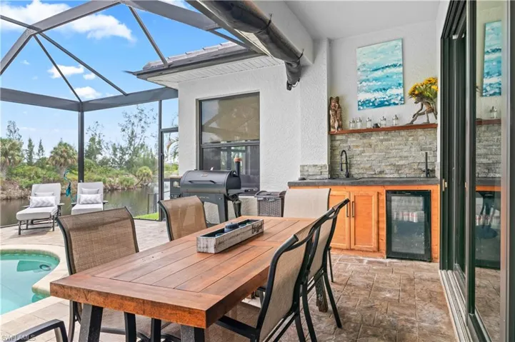 View of patio with an outdoor pool, outdoor dining space, a sunroom, a lanai, and wine cooler