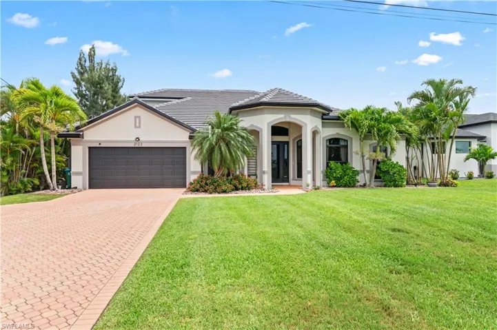 Mediterranean / spanish-style home featuring stucco siding, decorative driveway, a front yard, and a garage