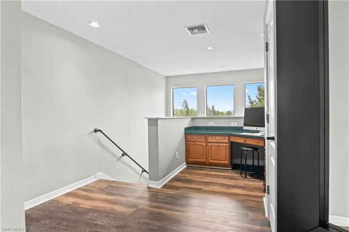 Unfurnished office featuring dark wood-style floors, built in study area, and recessed lighting