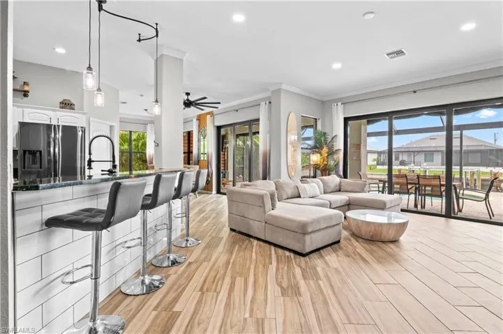 Living room featuring wood finish floors, recessed lighting, ornamental molding, and a ceiling fan