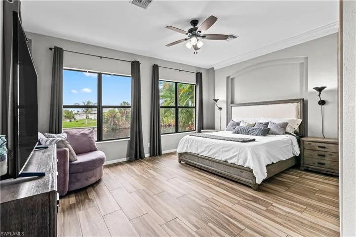 Bedroom with wood finish floors, a ceiling fan, and ornamental molding