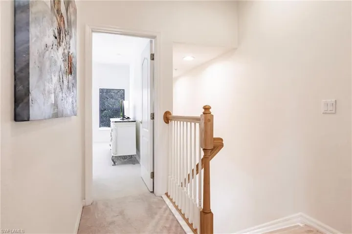 Hallway featuring light colored carpet and an upstairs landing