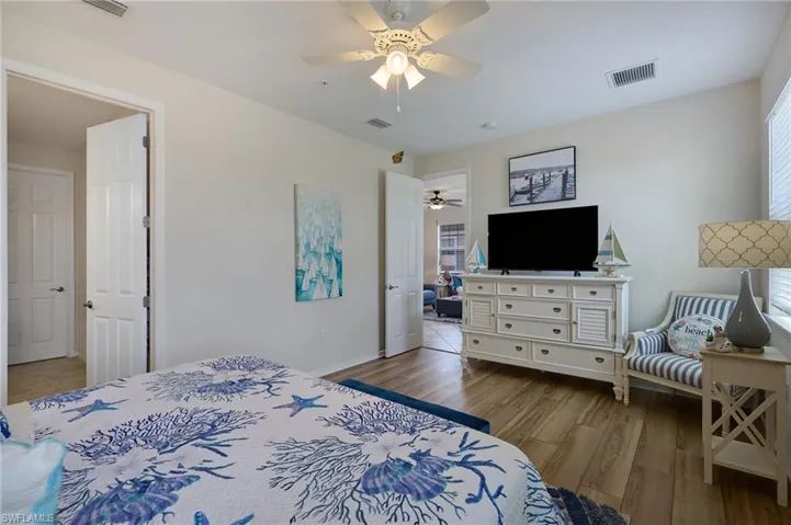 Bedroom with a ceiling fan, wood finished floors, baseboards, and visible vents
